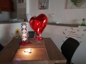 un corazón rojo sentado sobre una mesa con una vela en A casa di Grazia, en Vitorchiano