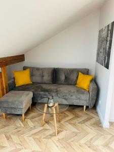 - un salon avec un canapé gris et des oreillers jaunes dans l'établissement Apartament MM MIEJSCE PARKINGOWE, à Gorzów Wielkopolski