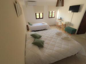 1 dormitorio con 1 cama blanca grande con almohadas verdes en Blanc Hotel Boutique en Salta