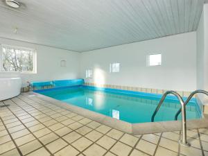 een groot zwembad met blauw water in een kamer bij Holiday Home Hedevang V in Oksbøl