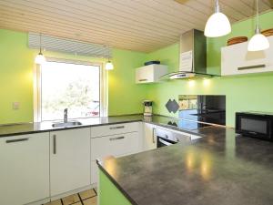 OksbølにあるHoliday Home Hedevang Vの緑の壁と黒いカウンタートップが備わるキッチン