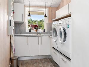 eine Küche mit weißen Schränken und einer Waschmaschine und einem Trockner in der Unterkunft 10 person holiday home in Fårevejle-By Traum in Fårevejle + 40 Fotos