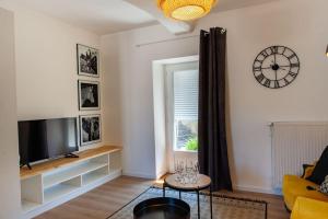 a living room with a television and a clock on the wall at Duplex contemporain dans maison du XVIIème siècle in Fougères