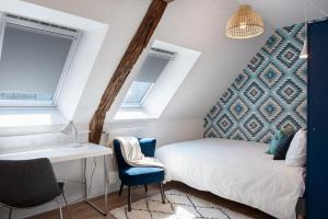 a bedroom with a bed and a desk and two windows at Duplex contemporain dans maison du XVIIème siècle in Fougères