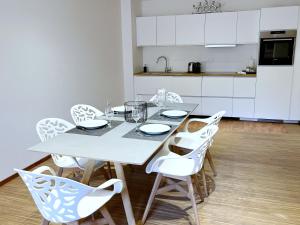 a white kitchen with a table and white chairs at Loft Saint Thomas - Petite France in Strasbourg