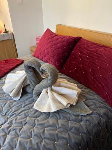 Una cama con toallas y almohadas rojas. en PIVOINE Chambre d hotes, en Fralignes