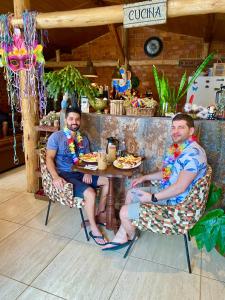 twee mannen aan een tafel in een restaurant bij Pousada Altitude 1200 in Fazendinha