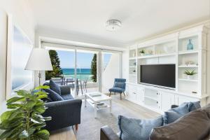 uma sala de estar com cadeiras azuis e uma televisão em Luxury Manly Beachfront Apartment em Sydney