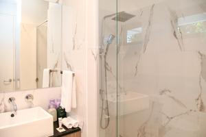 a white bathroom with a shower and a sink at Hilton Executive Apartments in Keswick