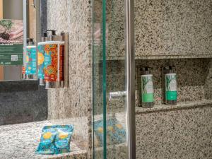 baño con cabina de ducha de cristal con 2 botellas en Pullman Sao Paulo Guarulhos Airport, en Guarulhos