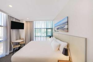 a hotel room with a large bed and a tv at Travelodge Hotel Sydney Airport in Sydney