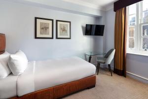 a hotel room with a bed and a table and a window at Radisson Blu Edwardian Bond Street Hotel, London in London