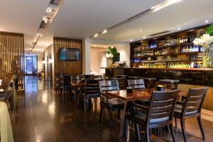 un restaurante con mesas y sillas de madera y un bar en Libertad Hotel Buenos Aires en Buenos Aires