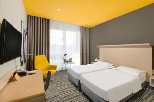 a hotel room with two beds and a flat screen tv at Park Inn By Radisson Budapest in Budapest