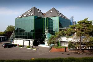 een groot glazen gebouw met een auto geparkeerd op een parkeerplaats bij Hotel & Loisir Le Ruote in Roveleto
