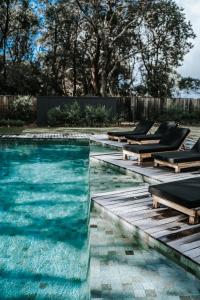 a swimming pool with chaise lounges and a swimming poolvisor at Bangalay Luxury Villas in Shoalhaven Heads