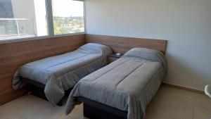 1 dormitorio con 2 camas y ventana en Patagonia Home en Cipolletti