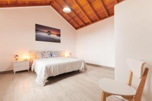 a white bedroom with a bed and a chair at Cantinho do Sossego in Madalena