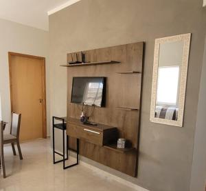 a living room with a tv and a desk and a mirror at Casa Sophia 17 ( Condomínio Aberto ) in Três Lagoas