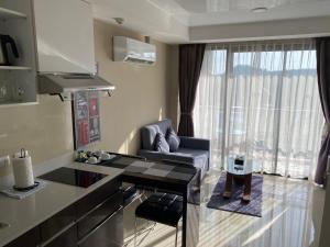 eine Küche und ein Wohnzimmer mit Sofa und Tisch in der Unterkunft AYA APARTMENTS IN MBC in Mai Khao Beach
