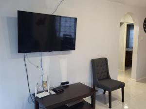 a living room with a chair and a television on a wall at Soleil Deluxe Hartland Home in Priory