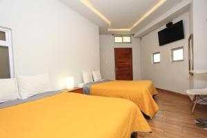 2 Betten in einem Hotelzimmer mit gelber Bettwäsche in der Unterkunft Hotel Grand Guanajuato in Guanajuato