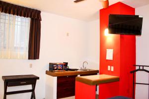 um quarto com uma parede vermelha com um lavatório e uma secretária em Real de la Presa em Guanajuato