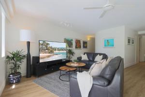 un soggiorno con divano e TV a schermo piatto di The Cove Noosa - Apartment 4 a Noosa Heads