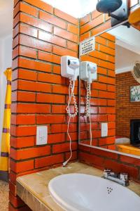 a bathroom with a brick wall with a sink at Hotel Posada el Cid in Oaxaca City