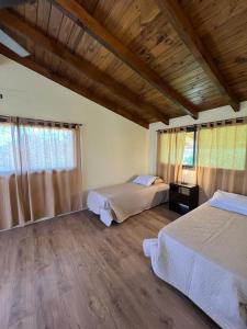 - une chambre avec deux lits et un plafond en bois dans l'établissement Las Tres Rosas Casa de Campo, à Falda del Carmen