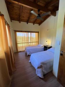 1 dormitorio con 2 camas, ventana y techos de madera en Las Tres Rosas Casa de Campo en 