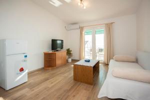 ein Wohnzimmer mit einem weißen Kühlschrank und einem TV in der Unterkunft Apartments with a parking space Grebastica, Sibenik - 13978 in Bašelovići