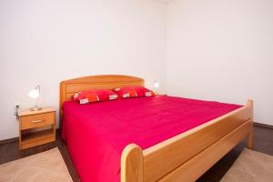 Schlafzimmer mit einem Holzbett mit roter Bettwäsche und roten Kissen in der Unterkunft Apartments with a parking space Grebastica, Sibenik - 13978 in Bašelovići