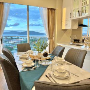 a dining room table with chairs and a large window at AruSuites Tanjung Aru Kota Kinabalu - Laxzone Suite in Kota Kinabalu