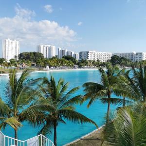 vistas a una piscina con palmeras y edificios en Lulu Village - Beach - Pool - Pet Friendly en Coclé