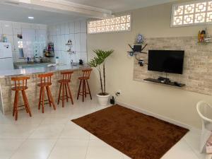 a kitchen with a bar with stools and a tv at Linda casa em Tarituba in Paraty