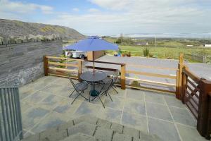 a patio with a table and an umbrella at Bwthyn Llys Twrog in Moel-tryfan