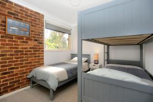 a bedroom with two beds and a brick wall at Tranquil Times in Tea Gardens