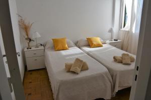 2 camas en una habitación blanca con almohadas amarillas en La Cañada en Córdoba