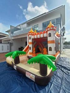 um parque insuflável com um castelo em frente a um edifício em Desaru Nova Guest House with BBQ and Near Tanjung Balau Beach em Bandar Penawar