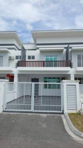 Uma casa branca com um portão à frente. em Desaru Nova Guest House with BBQ and Near Tanjung Balau Beach em Bandar Penawar