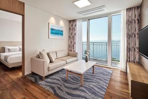 a living room with a couch and a bed and windows at Lotte Resort Sokcho in Sokcho