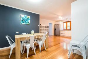 uma sala de jantar com uma mesa de madeira e cadeiras brancas em 200m to Tallebudgera Creek - Hosted by Burleigh Letting em Gold Coast