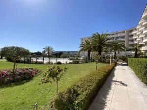 einen Gehweg in einem Park mit Palmen und einem Gebäude in der Unterkunft Appartement Juan les Pins, 2 pièces, 4 personnes - FR-1-252-169 in Antibes