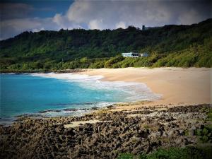 een strand met een huis op een heuvel naast de oceaan bij Kenting Sand Island W-Villa Seaview Resort in Fan-tzu-liao