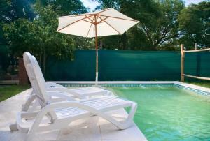 a pair of chairs and an umbrella next to a swimming pool at Casa La Jauría in Colonia Benítez