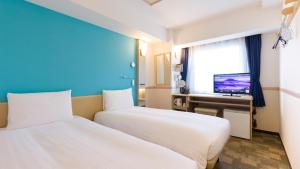 a hotel room with two beds and a television at Toyoko Inn Matsudo eki Higashi guchi in Matsudo