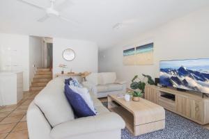 un soggiorno con due divani bianchi e una TV di The Cove Noosa - Apartment 16 a Noosa Heads