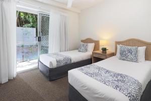 una camera d'albergo con due letti e una finestra di The Cove Noosa - Apartment 16 a Noosa Heads
