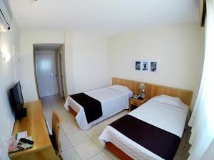a hotel room with two beds and a table at Harbor Self Graciosa Hotel in Quatro Barras